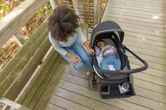 Woman looking on as child sleeps in the Pivot Xplore Dreamz All-Terrain Stroller Wagon with Bassinet Insert