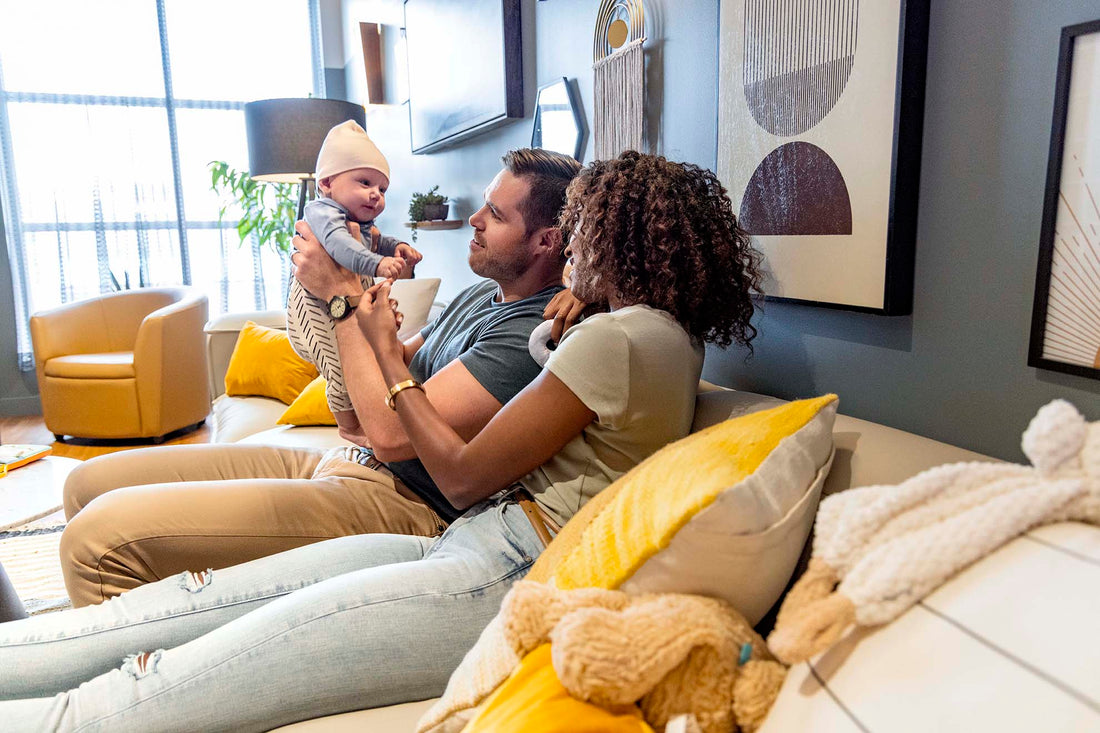 Man holding baby with woman looking on while sitting on the couch