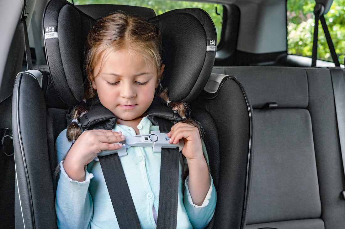 Girl buckling her SensorSafe chest clip while sitting in her Revolve360 Extend All-in-One Rotational Convertible Car Seat in forward-facing mode