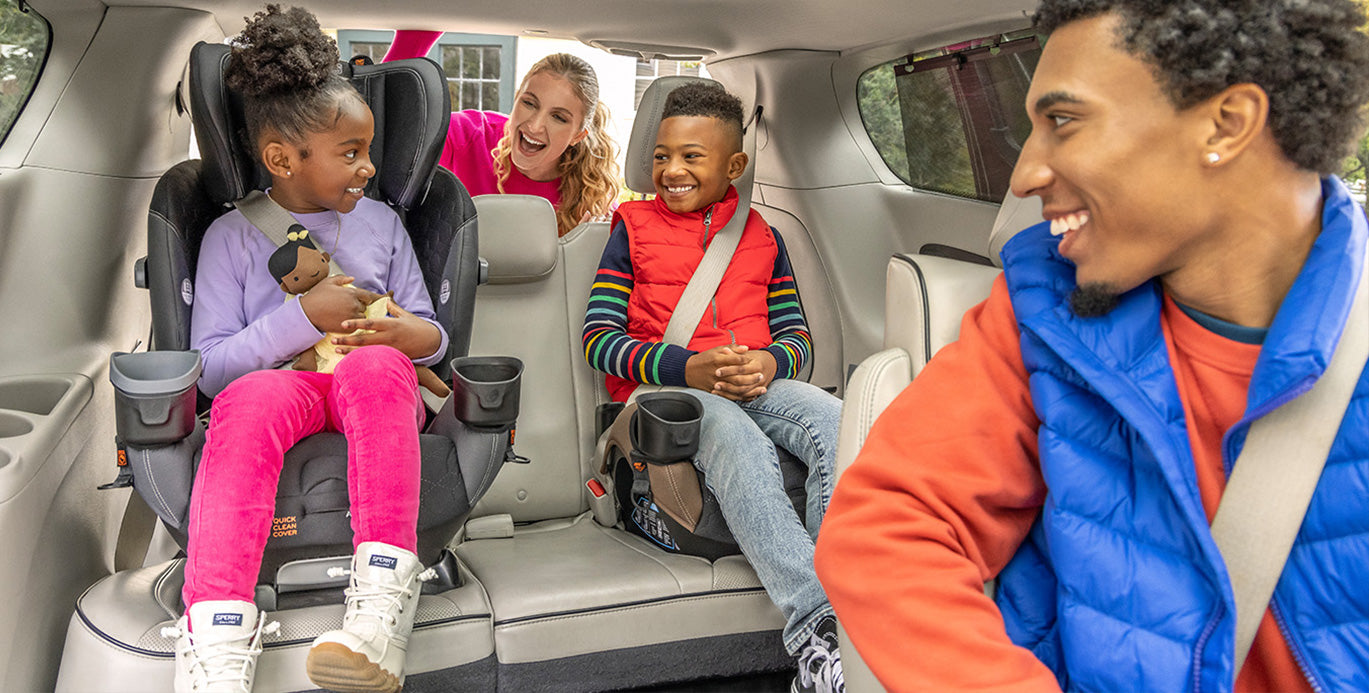 two children sitting in Evenflo car seats in the backseat of a car