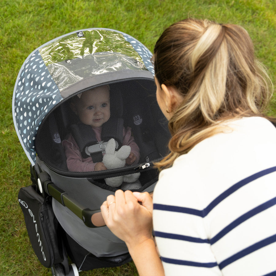Baby in Evenflo Shyft DualRide stroller with all-weather cover